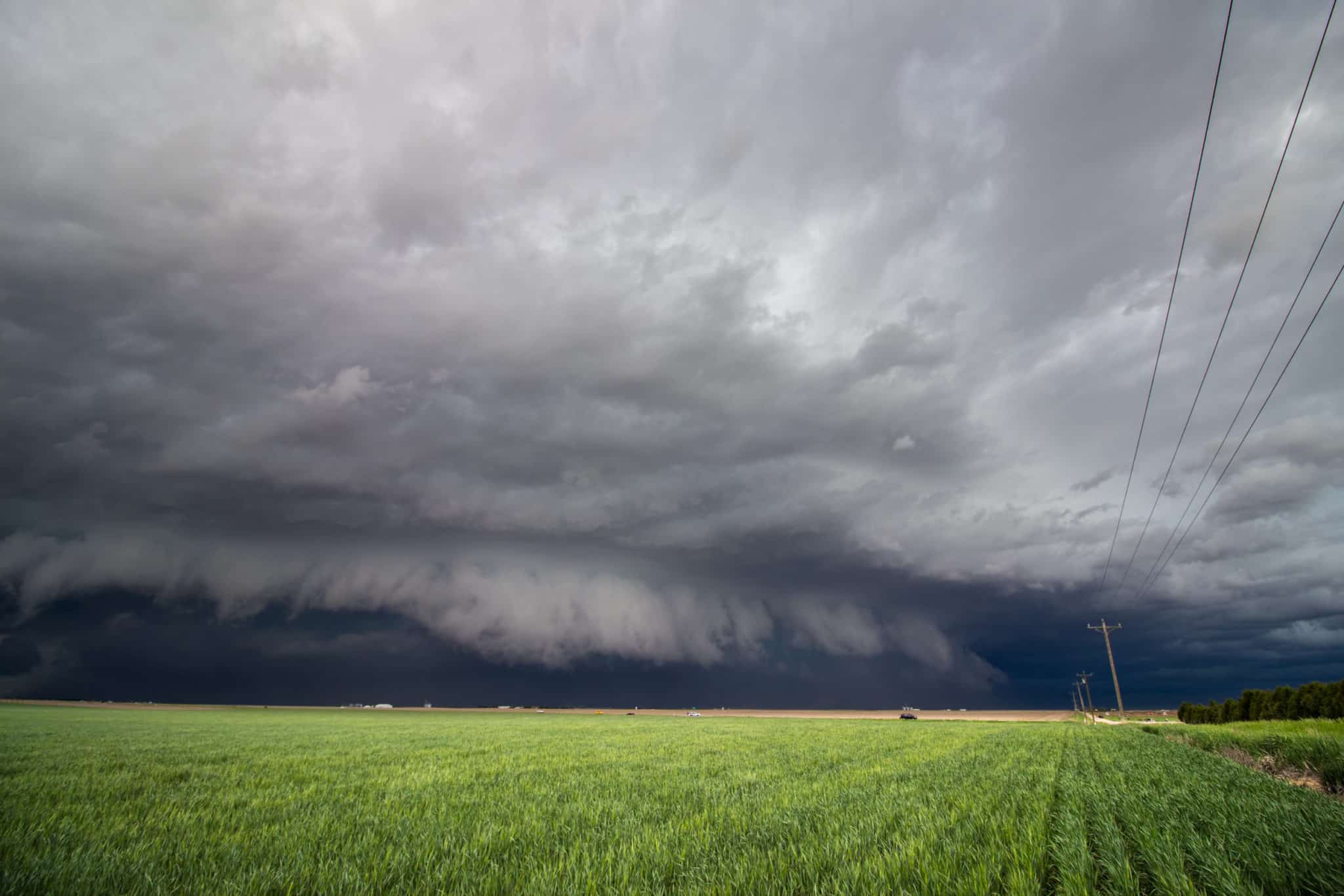 A low shelf cloud and severe storm rapidly approaches over farm country